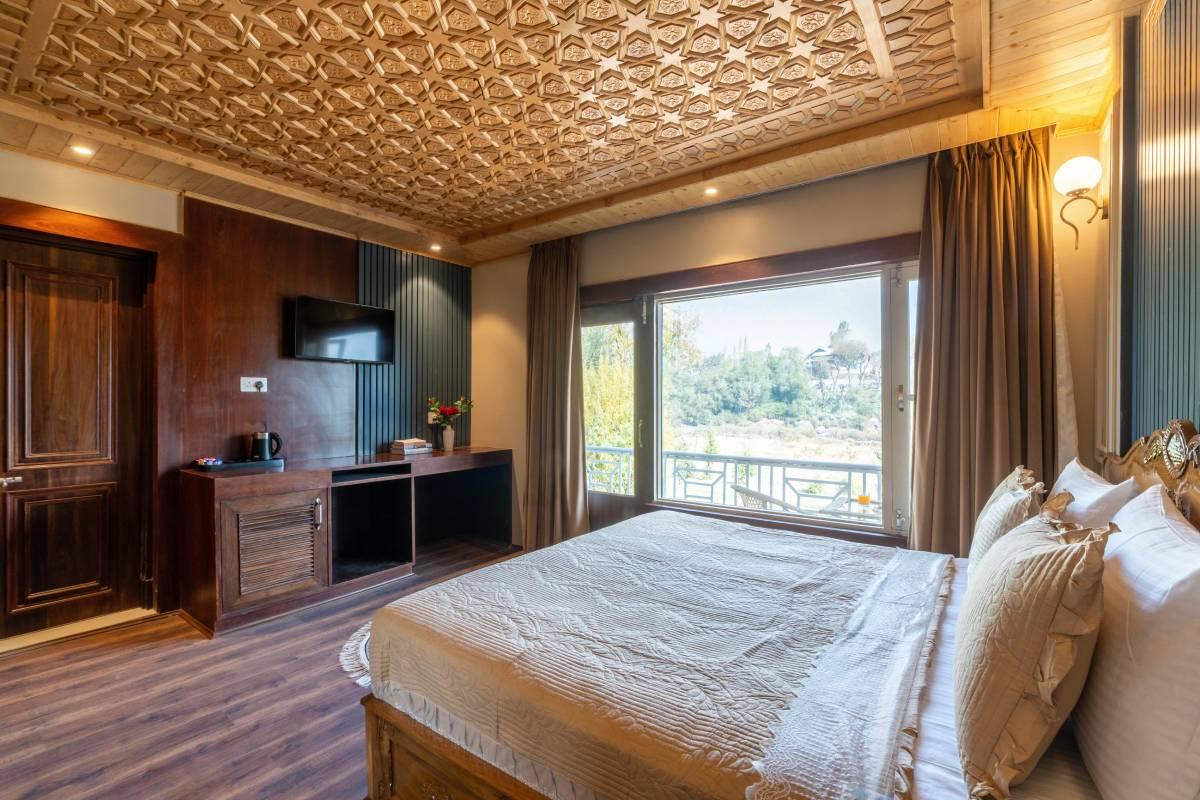 Super Deluxe bedroom with carved khatamband ceiling and a window onto the balcony and garden | Khwab Villa, Kangan, Kashmir Super Deluxe bedroom with carved khatamband ceiling and a window onto the balcony and garden