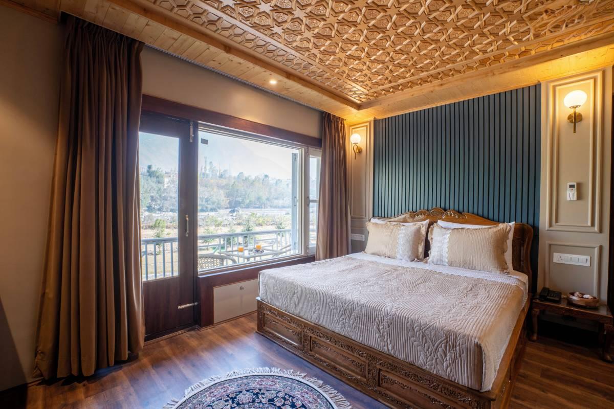 Super Deluxe bedroom with carved wooden bed and mountain-facing windows | Khwab Villa, Kangan, Kashmir Super Deluxe bedroom with carved wooden bed and mountain-facing windows